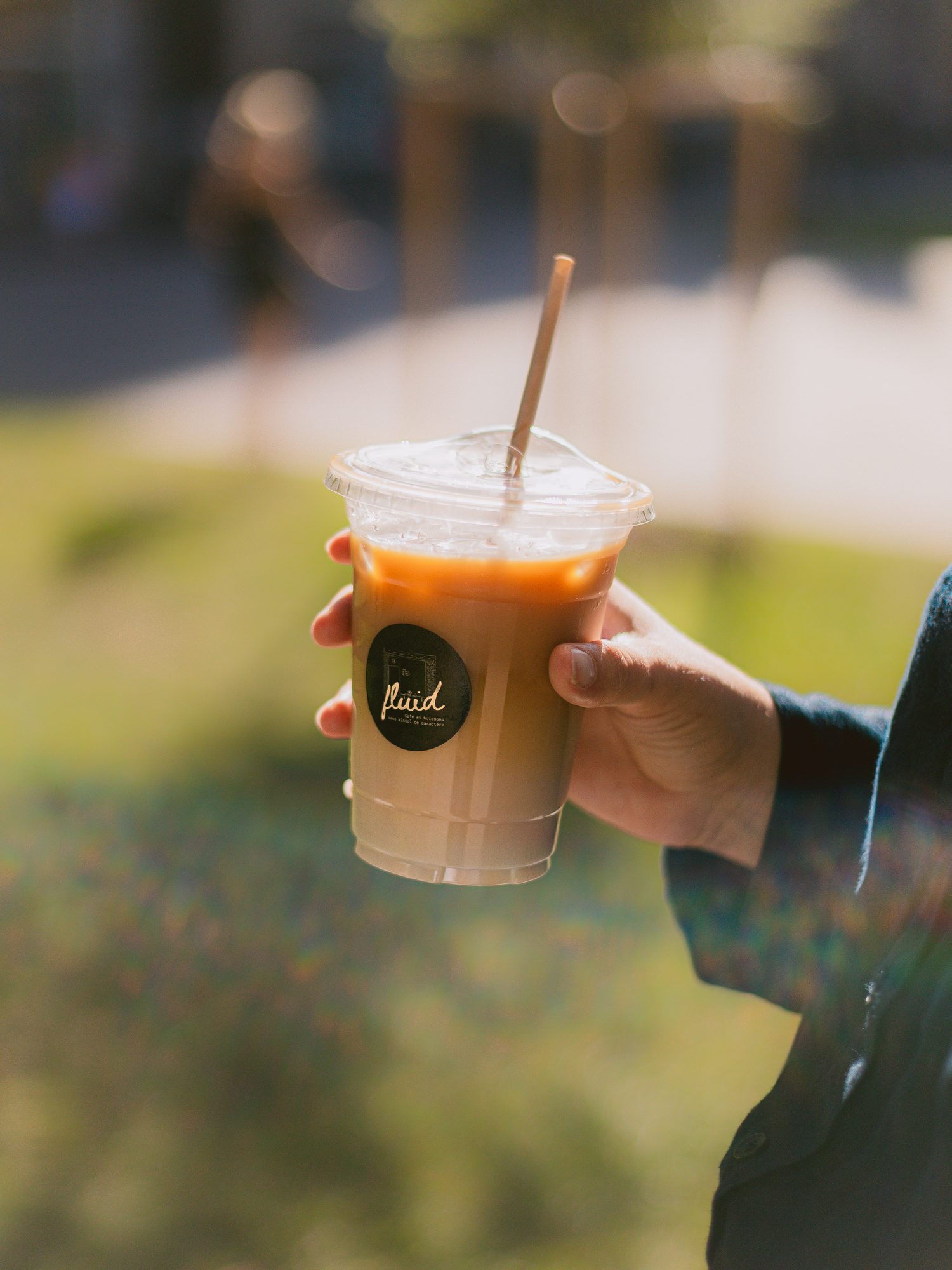 Un latte glacé Fluid tenu à la main au soleil